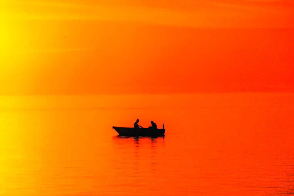 silhouette of two person riding on boat during golden hour
