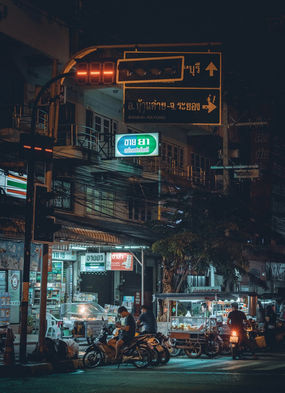 men sitting on their motorcycles under signages at night