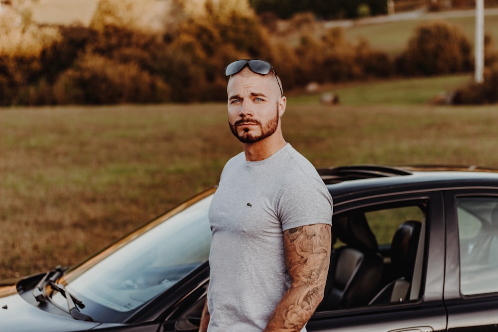 man standing beside car wearing gray crew-neck T-shirt