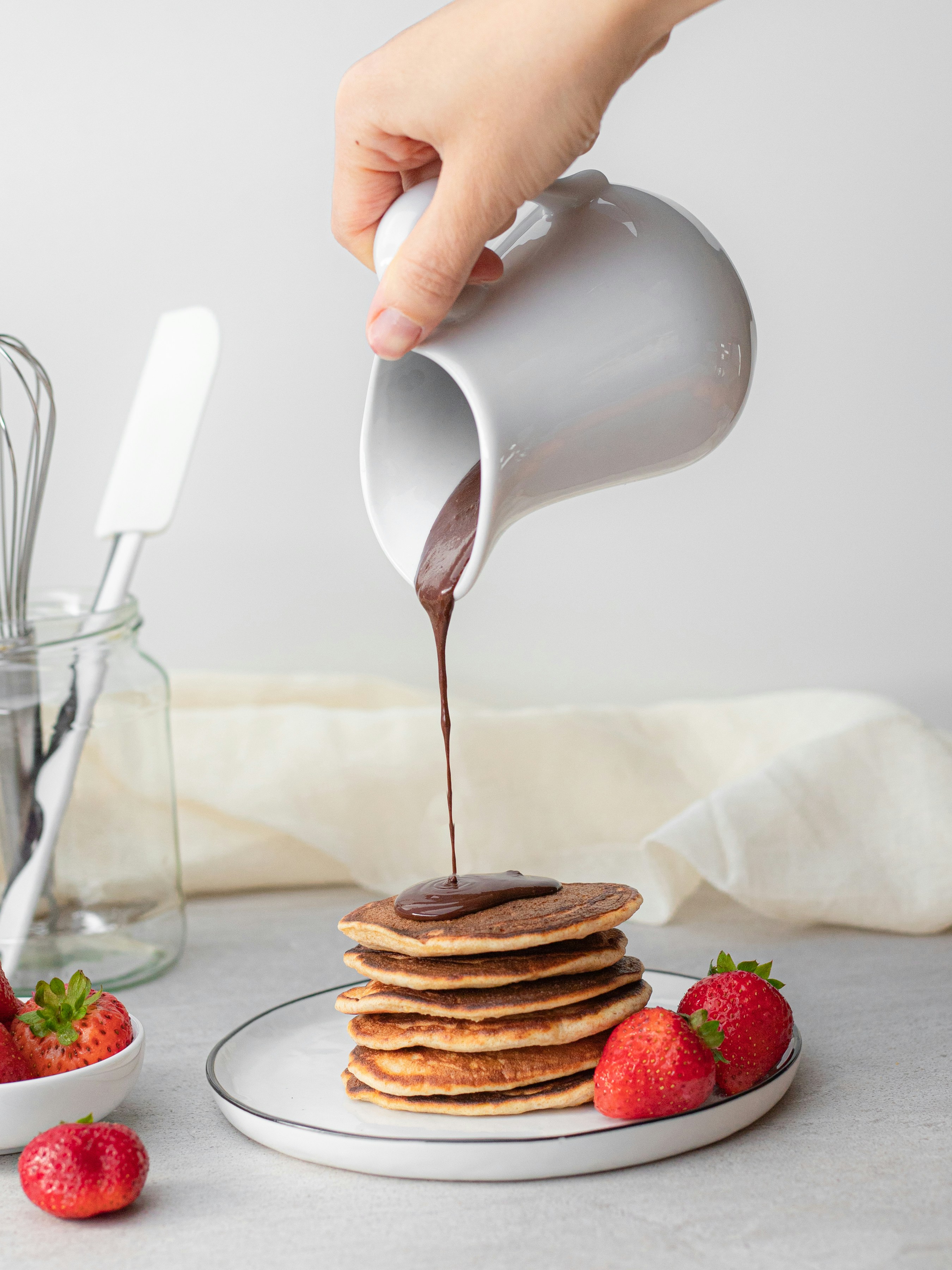 man pouring maple syrup on piled of pancake photo Free Food Image on