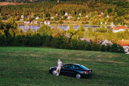 man stands and leans on car in Orfű Hungary