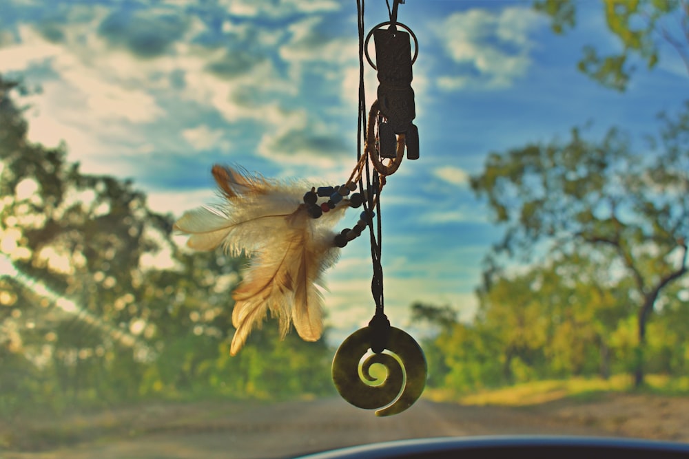 beige feather and necklace hanging car decor