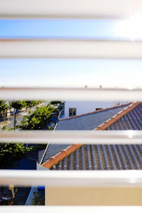 A contractor installing new windows on a sunny suburban home.