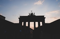 The iconic Brandenburg Gate glowing warmly at dusk in Berlin, framed by autumn trees.