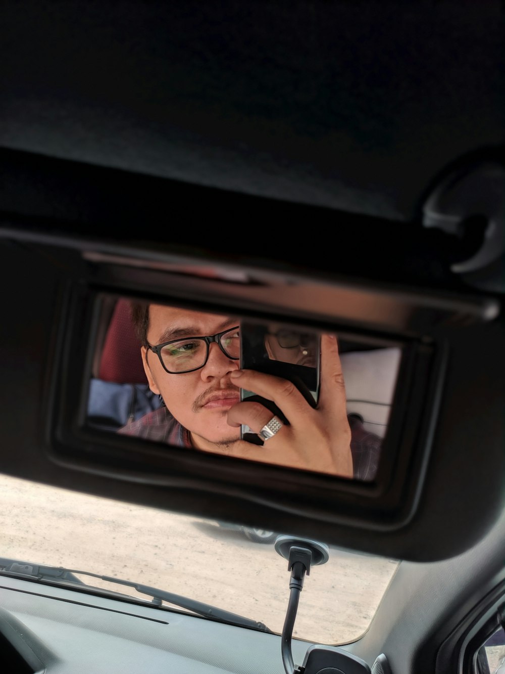 man wearing eyeglasses using phone while sitting