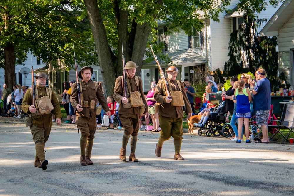 four soldiers marching on road carrying rifles