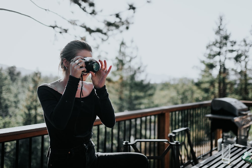 woman sitting beside balustrade taking photo