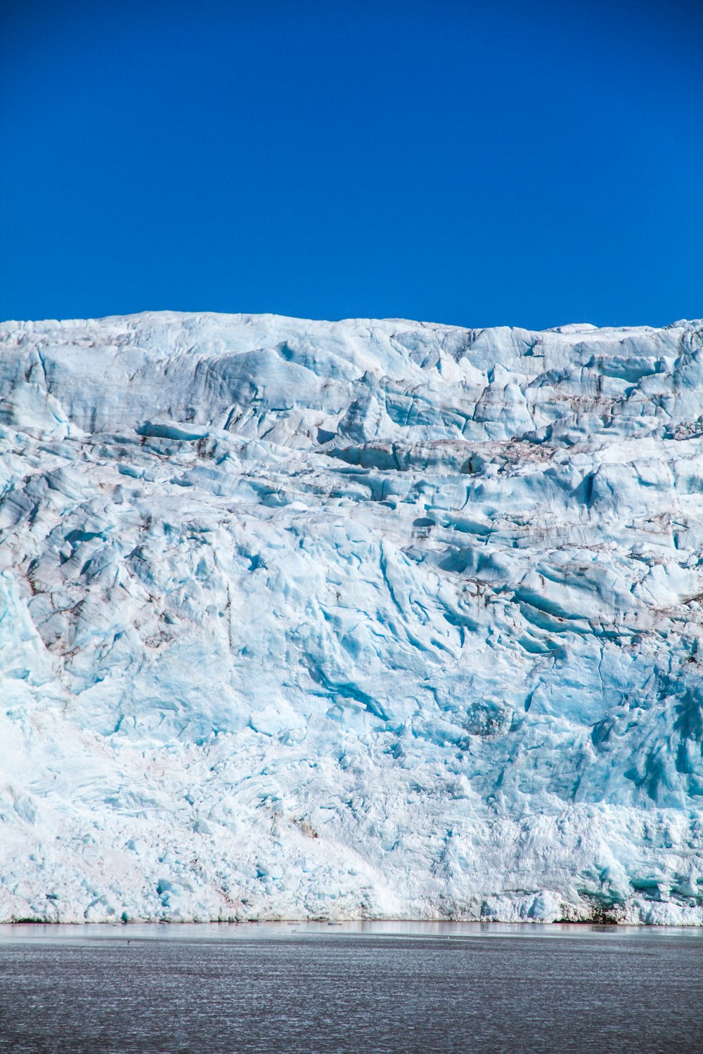 a large glacier with a boat in the water