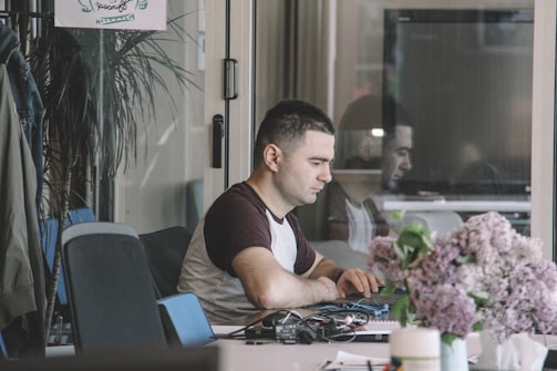 A candid photo of Mohit Singh working thoughtfully at his desk, surrounded by notes and a laptop.