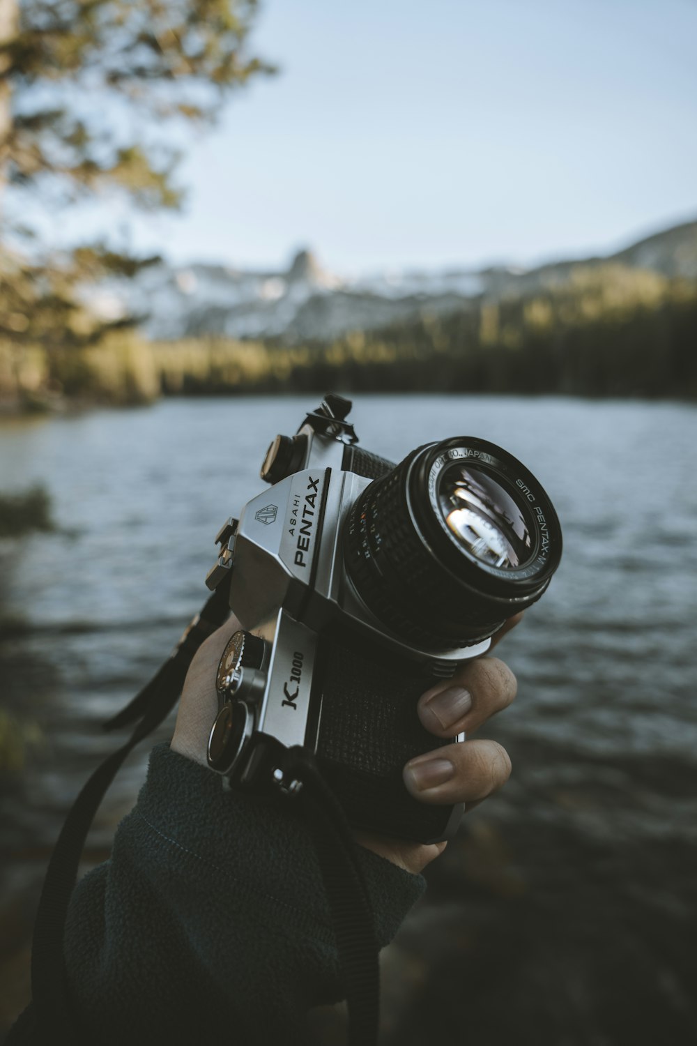 Persona che tiene la macchina fotografica nera e grigia