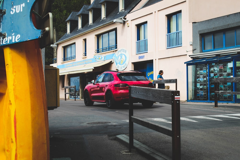 red SUV passing on road in front of store