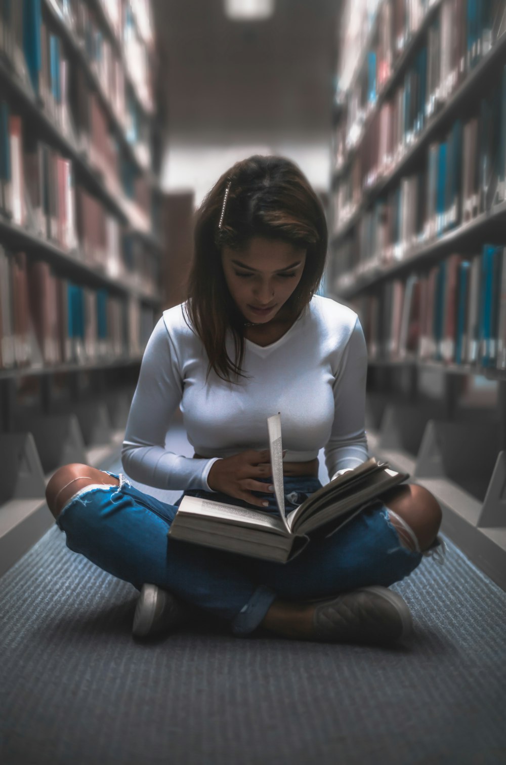 woman sitting between bookshelf