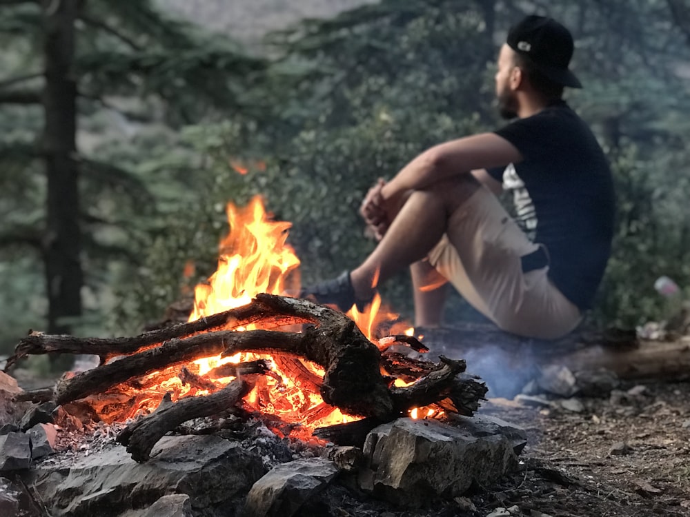 man sitting beside bonfire