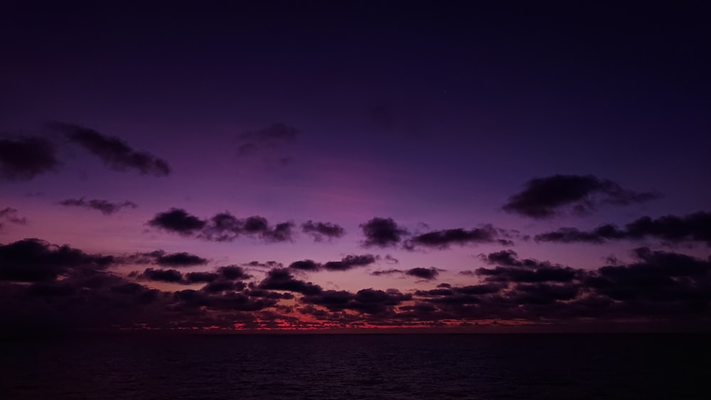 the sun is setting over the ocean with clouds