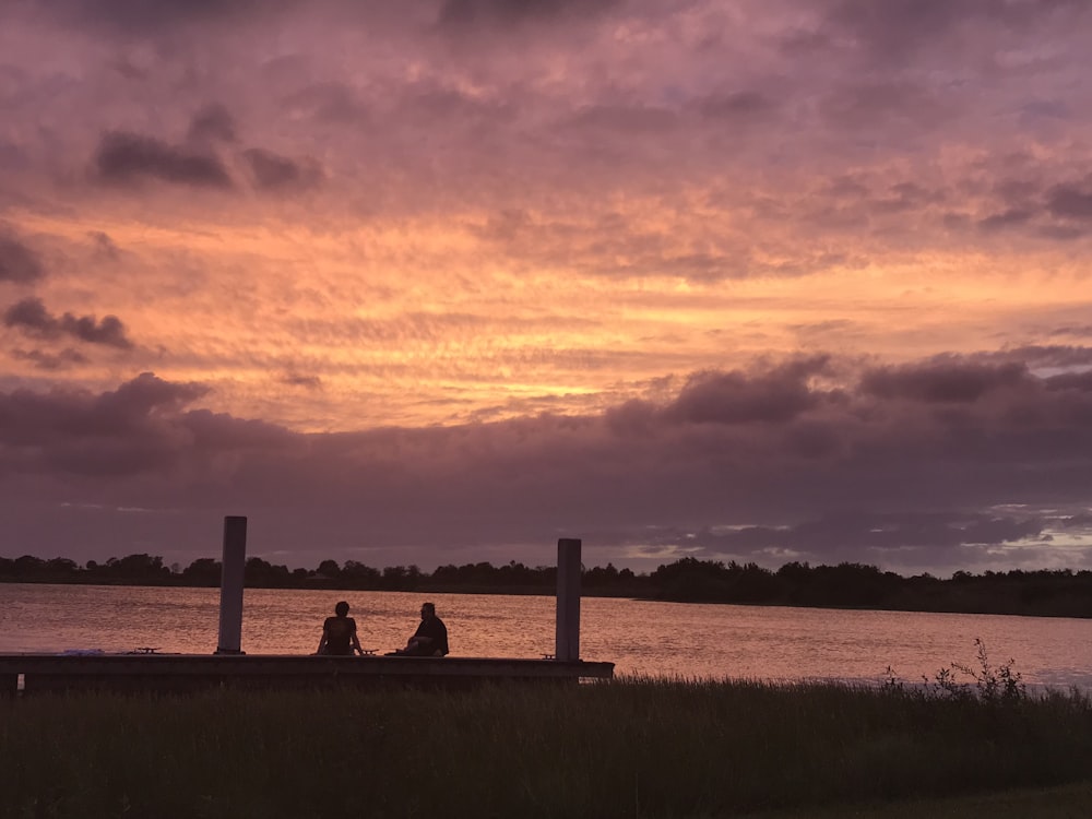 two people sitting near body of water