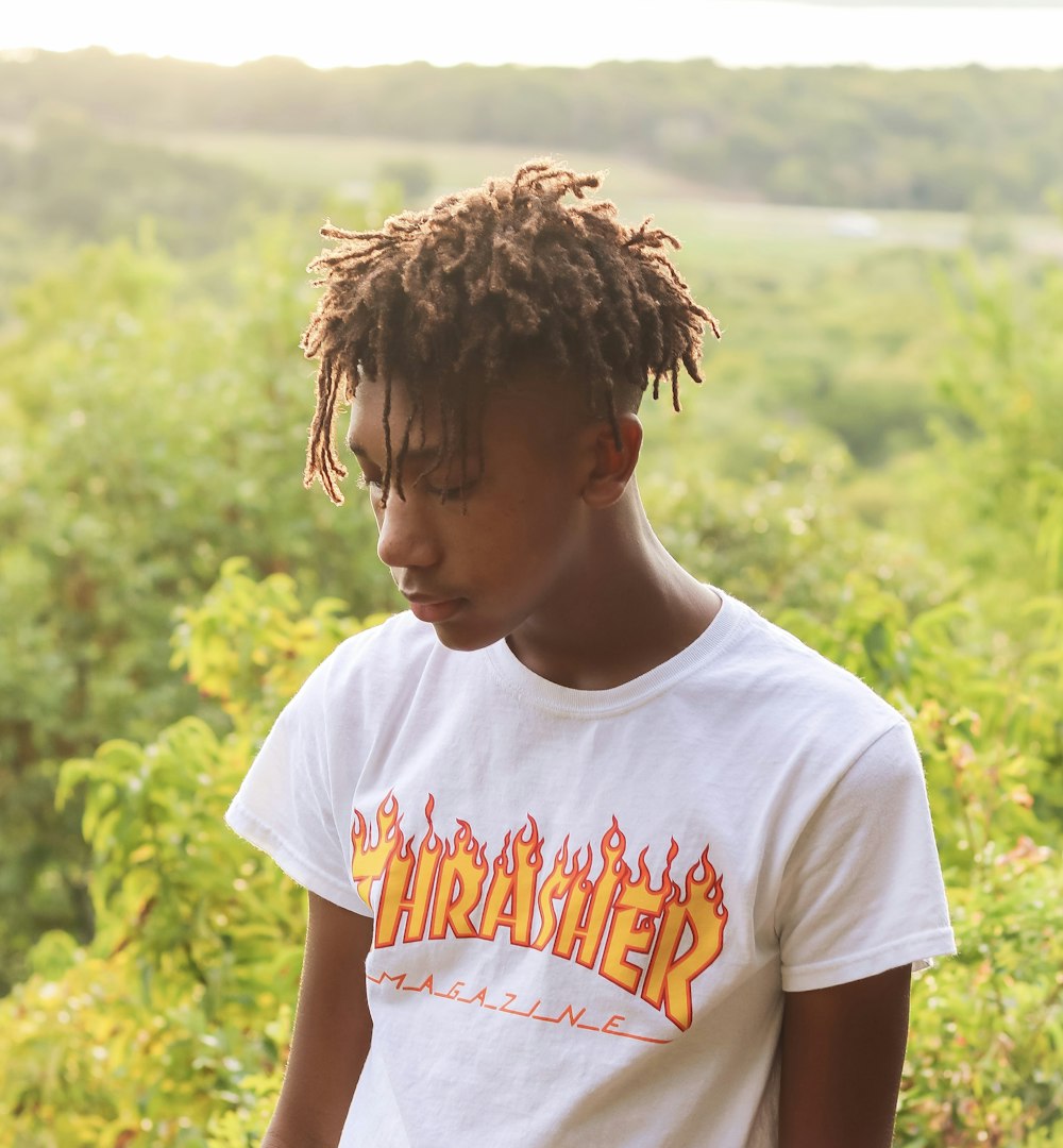 man wearing white t-shirt standing near tree