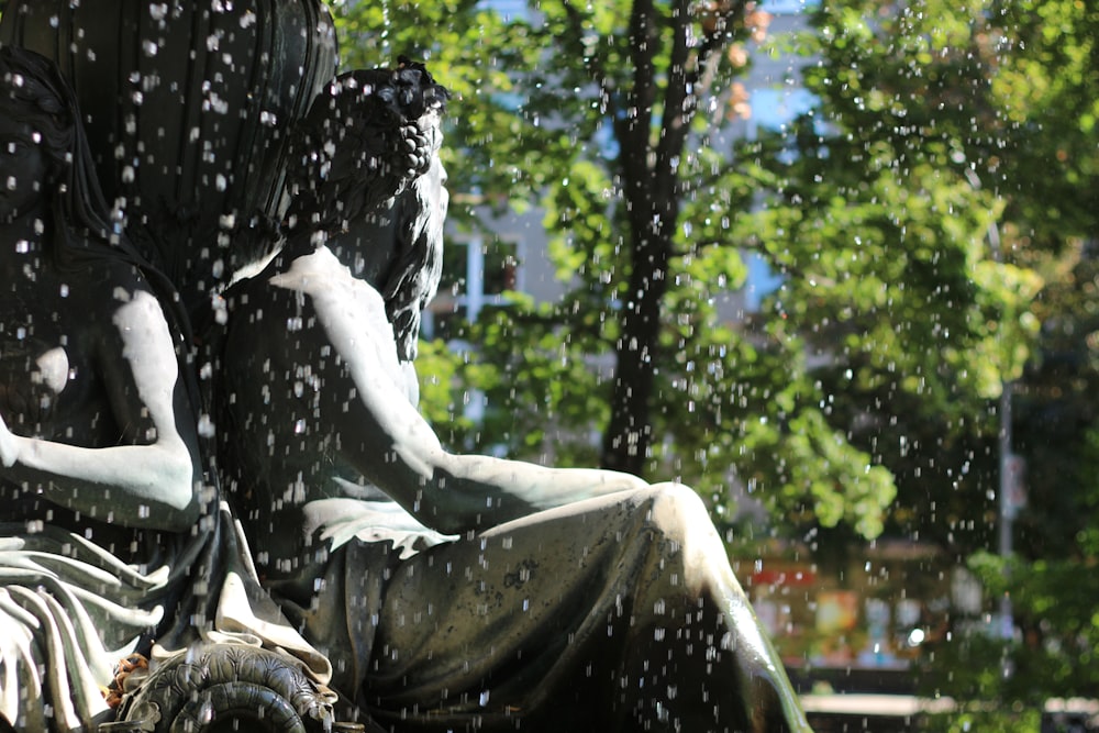 une statue d’une personne assise sous la pluie
