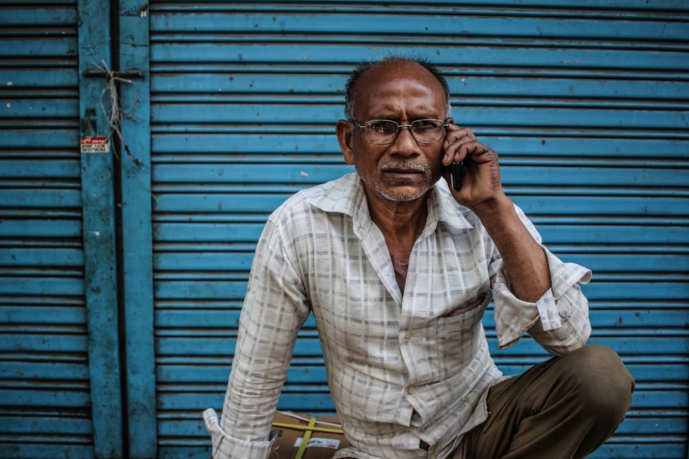 Hombre sentado con camisa gris sosteniendo el teléfono en la oreja