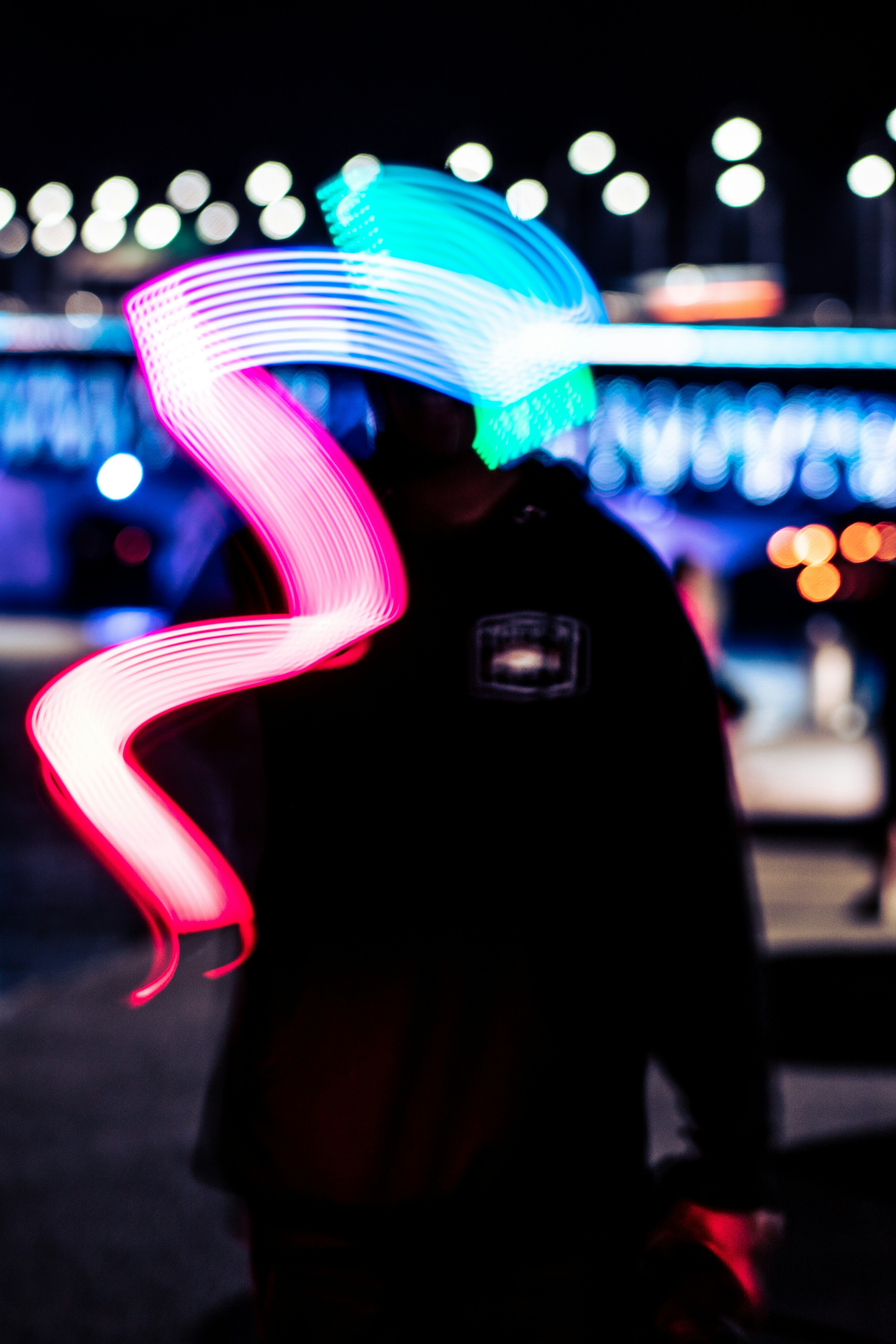 Persona urbana con hoodie deportivo caminando en ciudad nocturna con luces de neón