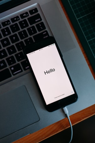 Phone with “Hello” screen on laptop—contact Imack Wedding Films, Glasgow wedding videographer.