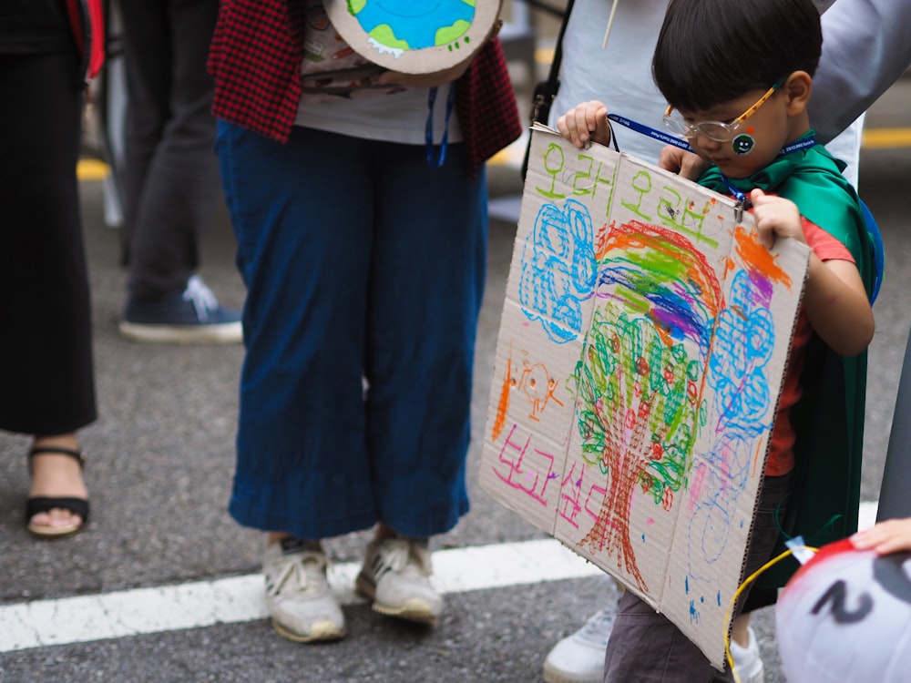 boy holding cardboard with drawings