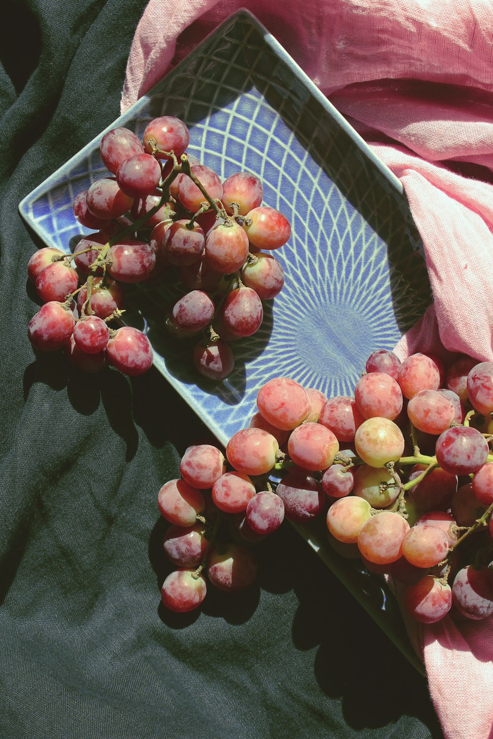 red grapes in plate on textile