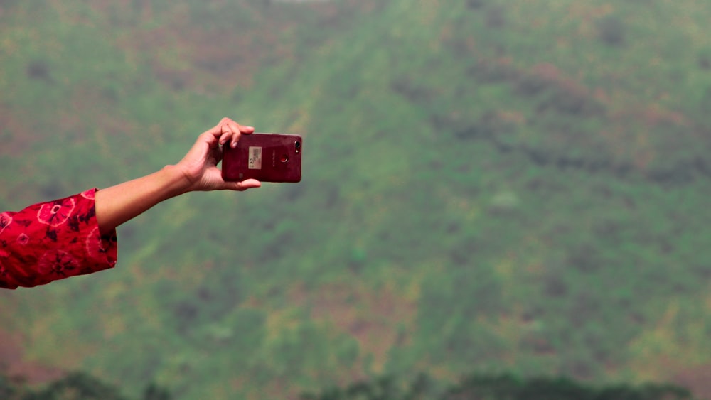 person holding maroon smartphone