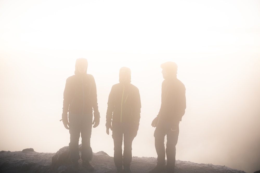 silhouette of three man on hill