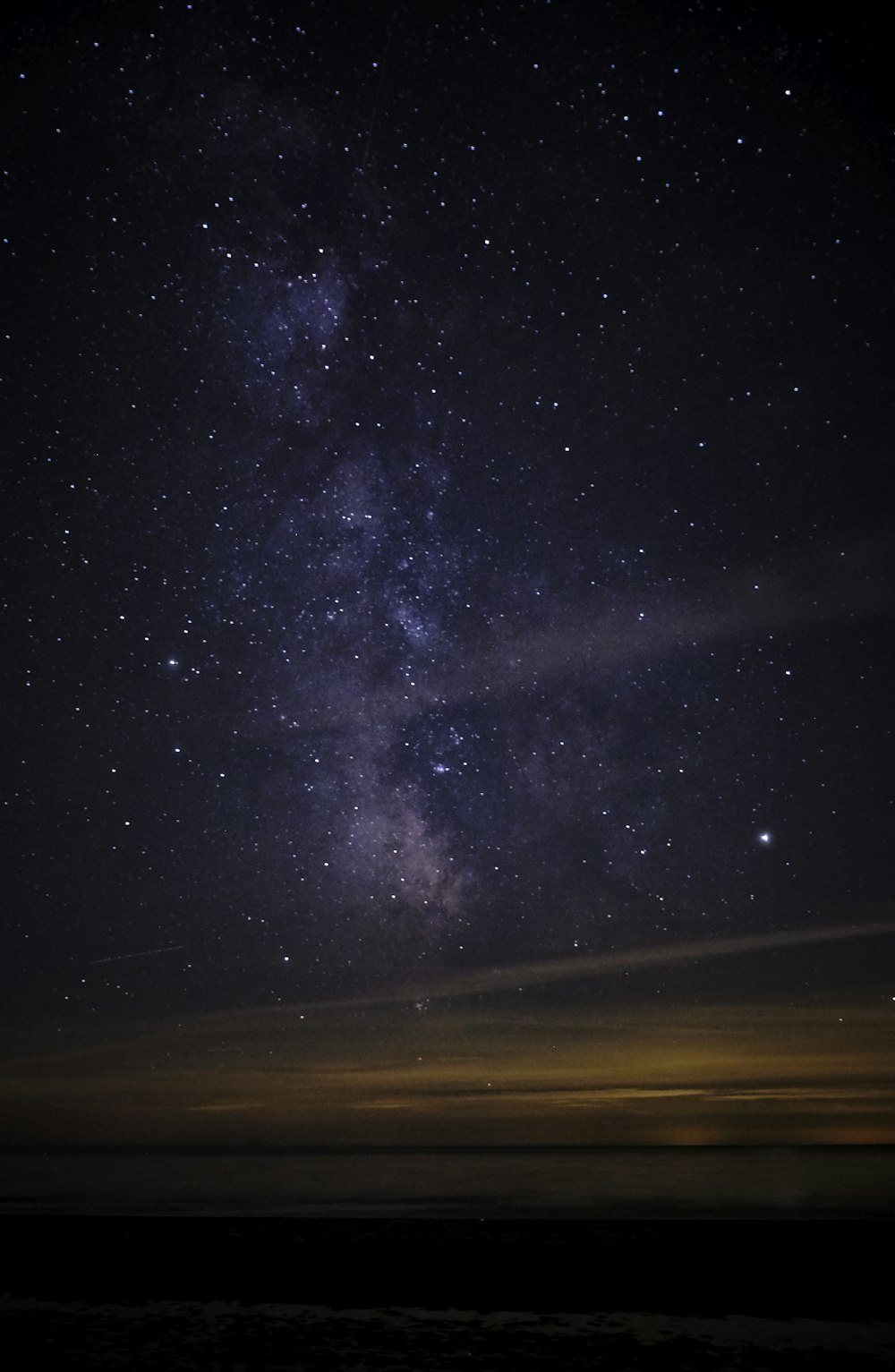 the night sky with stars above the ocean