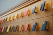 A well-organized display of mobile phones mounted on a wooden wall with various colored cases, arranged in rows with a sleek and modern lighting design accentuating the layout.