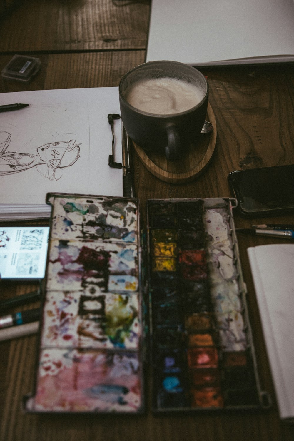 a wooden table topped with lots of art supplies