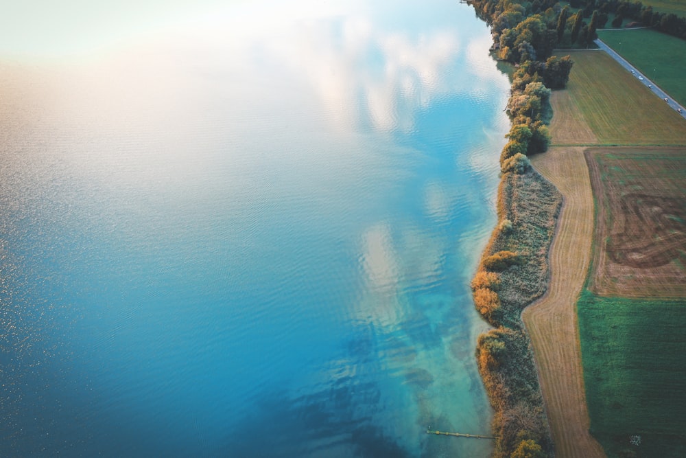 aerial photography of open field beside water during daytime