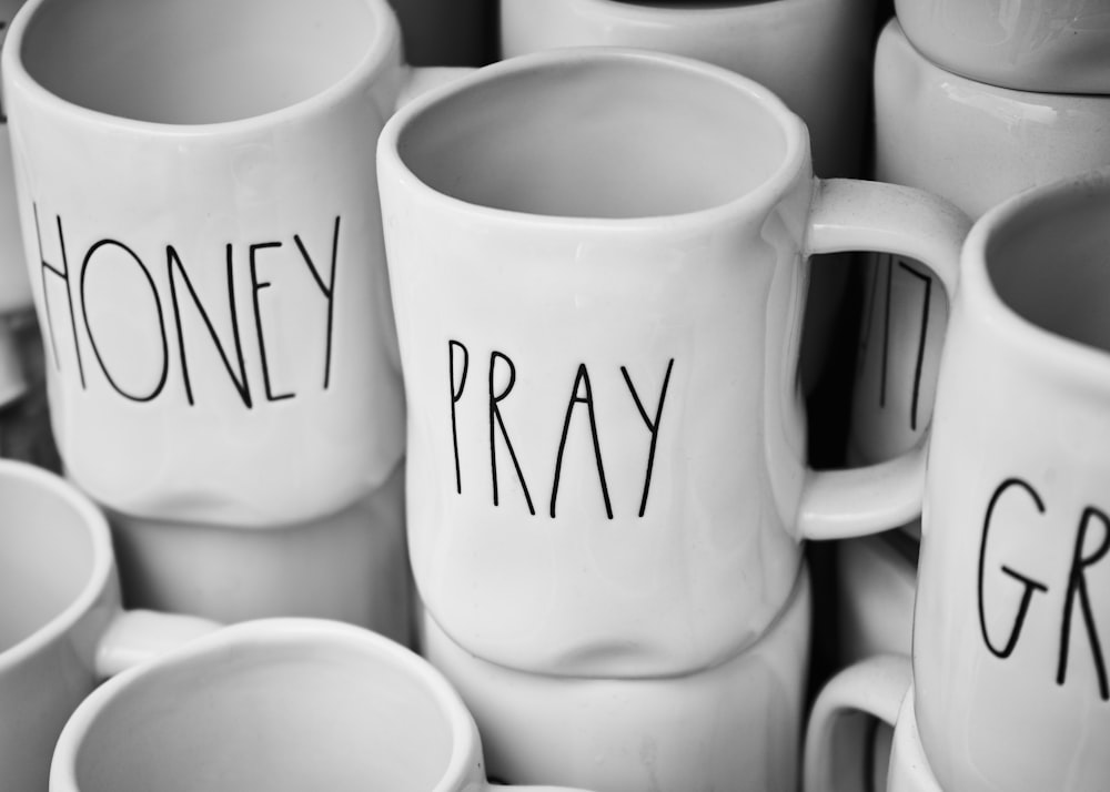 a pile of white coffee mugs with the word pray written on them