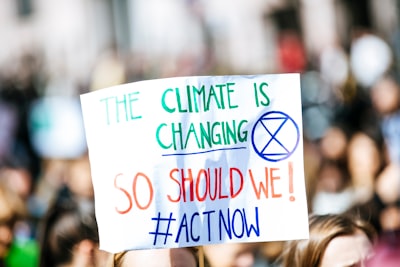 person holding the climate is changing signage political teams background