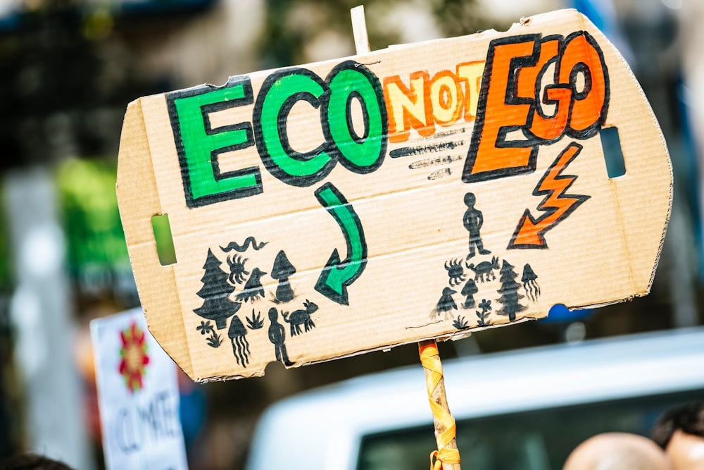 person holding Eco Not Ego signage