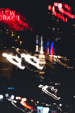 A dynamic behind-the-scenes shot of a Reel Time Promotions team member capturing a vibrant NYC event with neon-lit cityscape in the background.