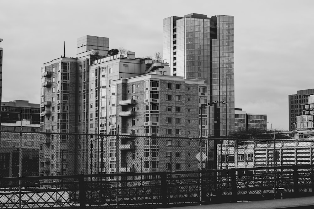 grayscale photography of high rise buildings near fence