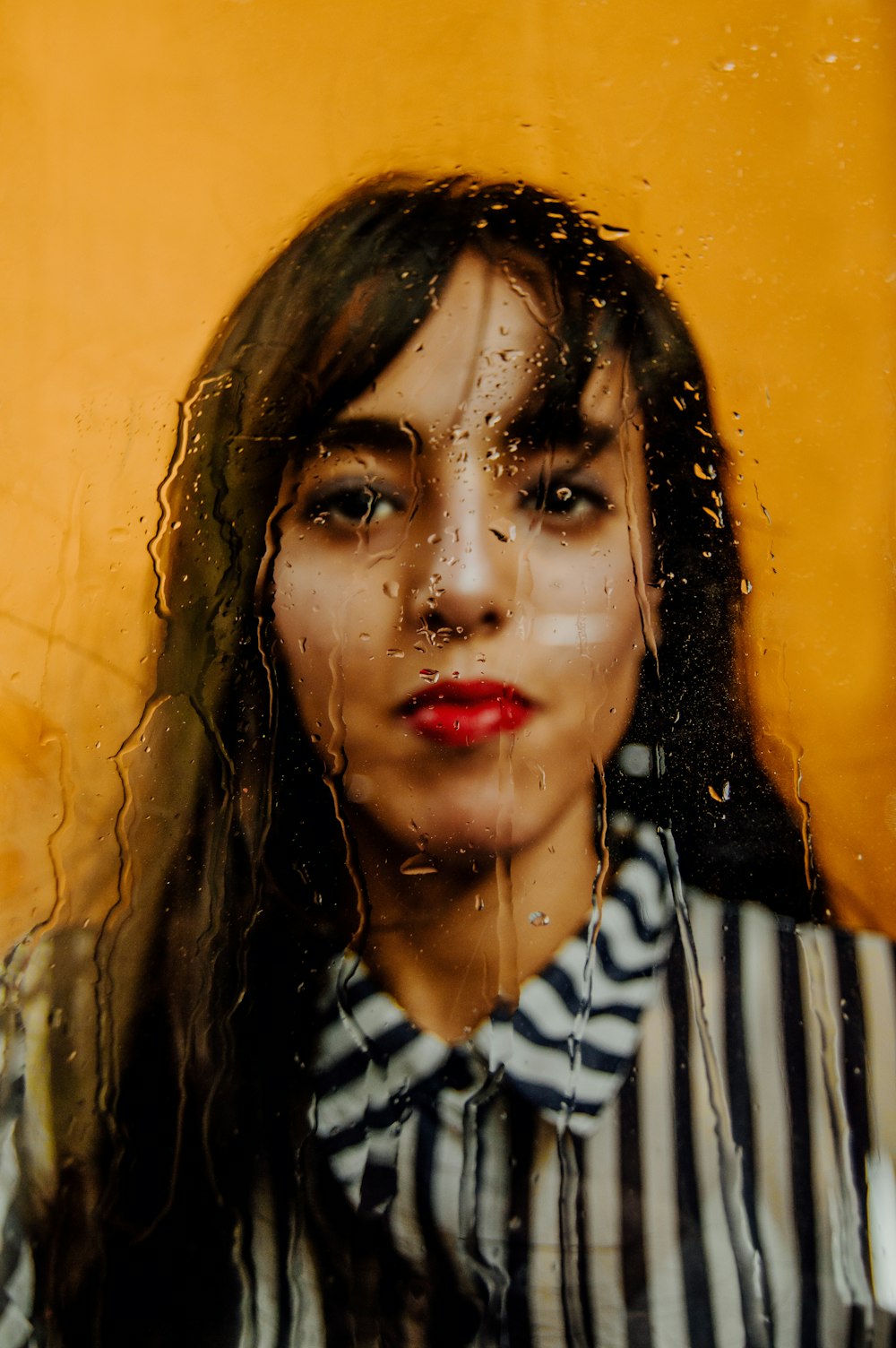 woman in black and white shirt behind glass