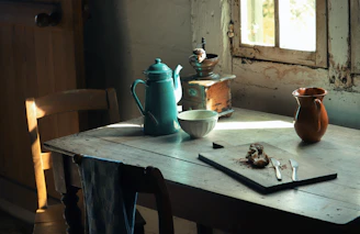 A rustic wooden table set with a steaming mug, a linen apron, and vintage bakery utensils bathed in soft morning light.