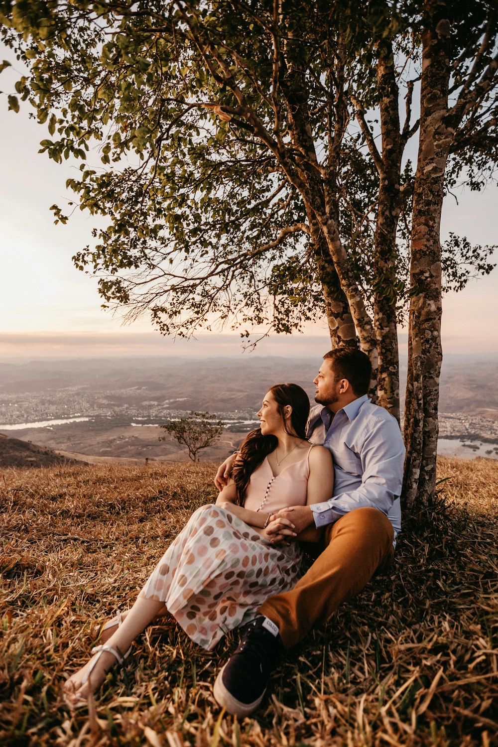 man and woman sitting beside trees