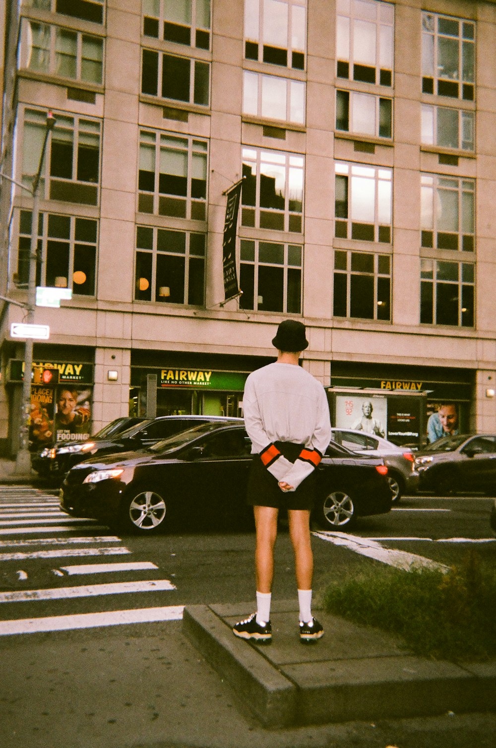 man wearing white sweater standing on sidewalk