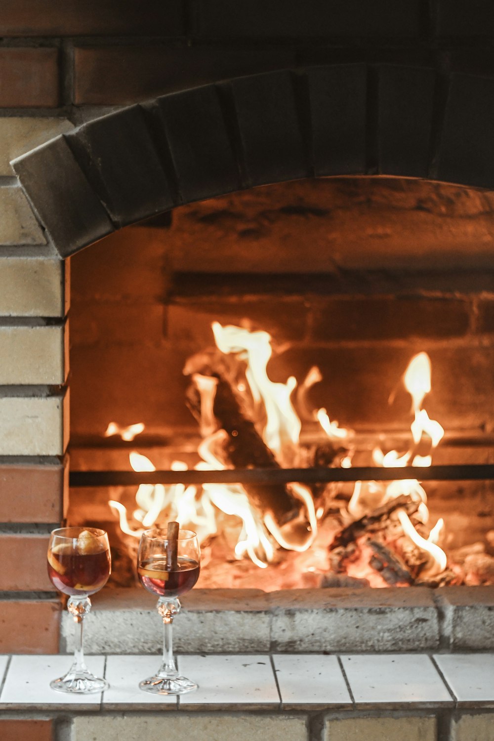 two filled wine glasses near fireplace