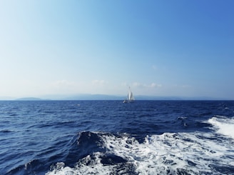 A sailing instructor guiding a small group of students on a bright day with sails raised.