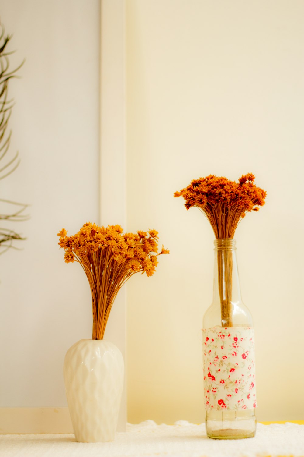 white ceramic vase besides clear glass bottle vase