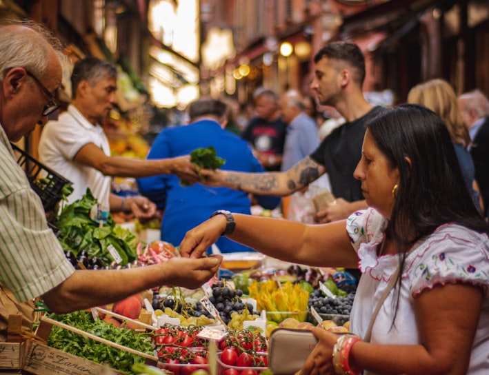 woman wearing white and red blouse buying some veggies