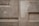 A textured concrete wall featuring rectangular patterns and subtle variations in color. The surface appears worn and slightly uneven with visible lines and angular shapes.