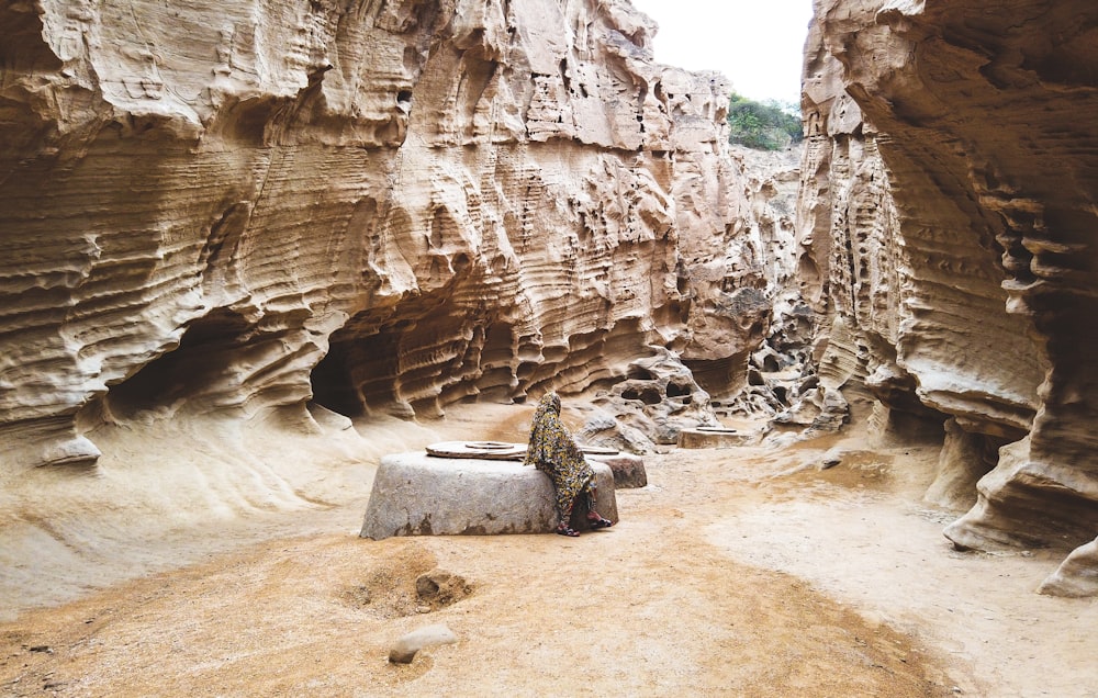 person sitting on rock between rock walls