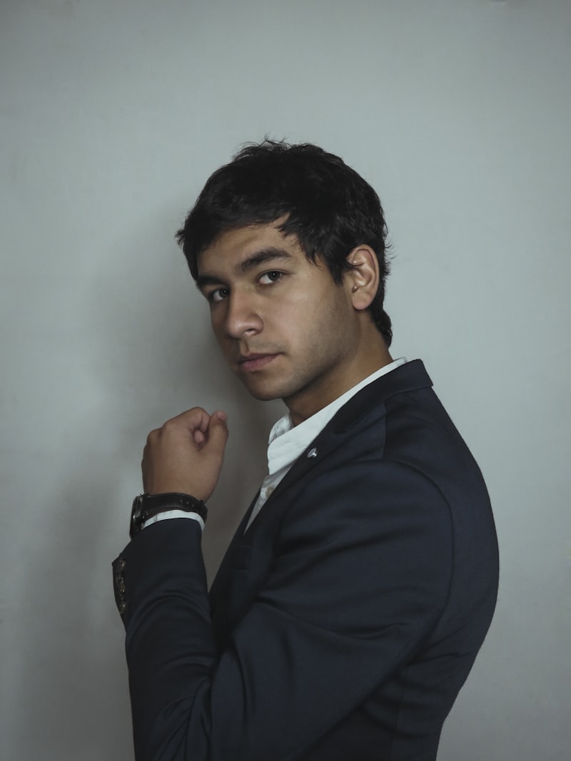 Hombre joven de saco oscuro mirando a la cámara