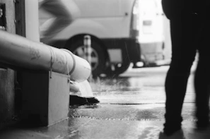 Team member inspecting and unclogging a rainwater drain outdoors