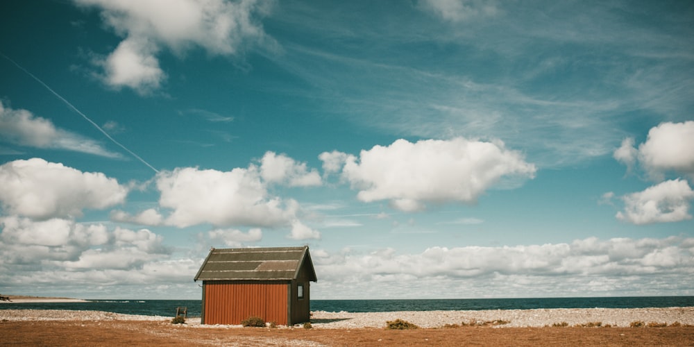 昼間は白と青の空の下、海岸近くの茶色い木造家屋